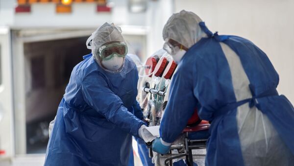 Врачи в защитных костюмах везут тяжелобольного в изоляционном боксе в палату интенсивной терапии в больнице с коронавирусом - Sputnik Казахстан