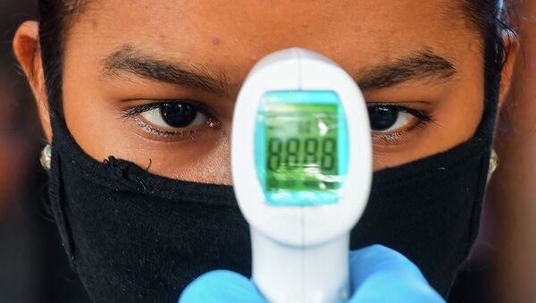 Девушка в маске ожидает, когда врач измерит ей температуру - Sputnik Казахстан