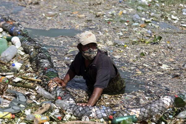 Сбор мусора, смытого дождями и удерживаемого барьером, установленным в одном из притоков озера в Аматитлане, Гватемала - Sputnik Қазақстан