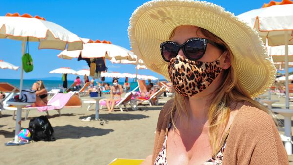 Женщина в защитной маске и солнцезащитных очках на пляже в Кастильоне-делла-Пеская, Италия - Sputnik Казахстан