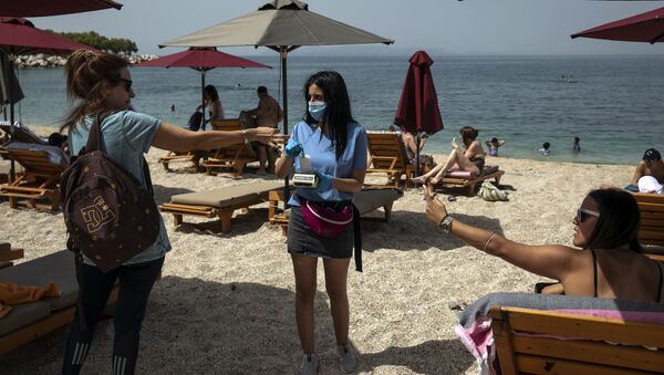 Посетительница оплачивает лежак на пляже в Афинах - Sputnik Казахстан