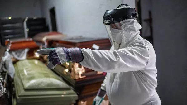 Сотрудник похоронного бюро в защитной экипировке работает в зале с гробами  - Sputnik Казахстан