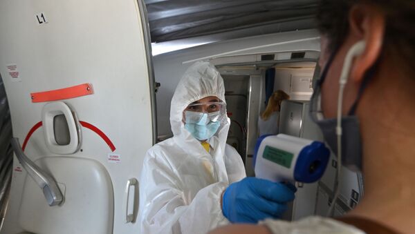 Медик в защитном костюме дистанционно измеряет температуру у пассажира перед посадкой в самолет  - Sputnik Казахстан
