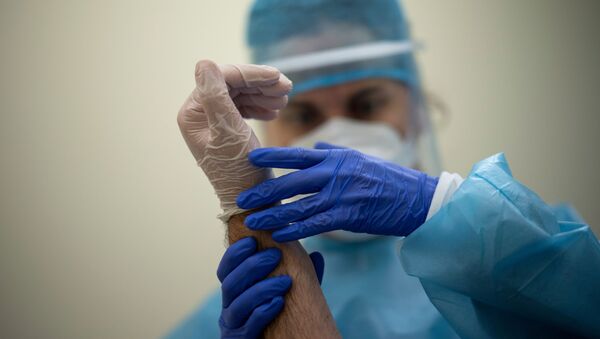 Врач в защитном костюме и маске держит руку пациента - Sputnik Казахстан