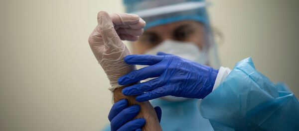 Врач в защитном костюме и маске держит руку пациента - Sputnik Казахстан