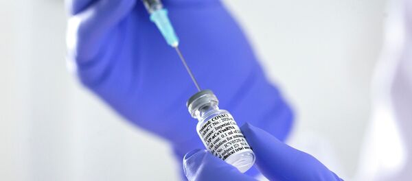 Сотрудник лаборатории набирает в шприц препарат во время испытания вакцины против коронавируса - Sputnik Казахстан