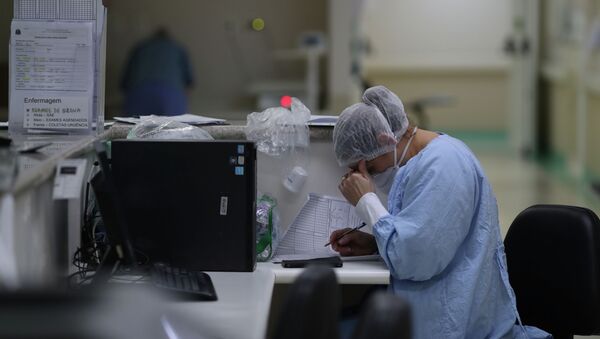 Врач в защитном костюме и маске работает с документами на сестринском посту в больнице с коронавирусом  - Sputnik Казахстан