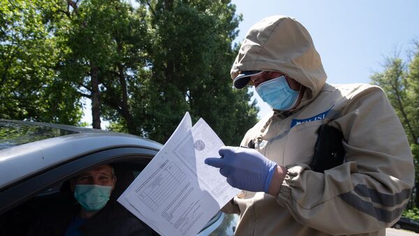 Полицейский в защитном костюме проверяет документы водителя  - Sputnik Казахстан