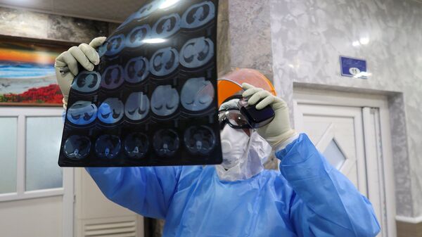 Медик в защитном костюме смотрит результаты МРТ в  больнице с коронавирусом - Sputnik Казахстан