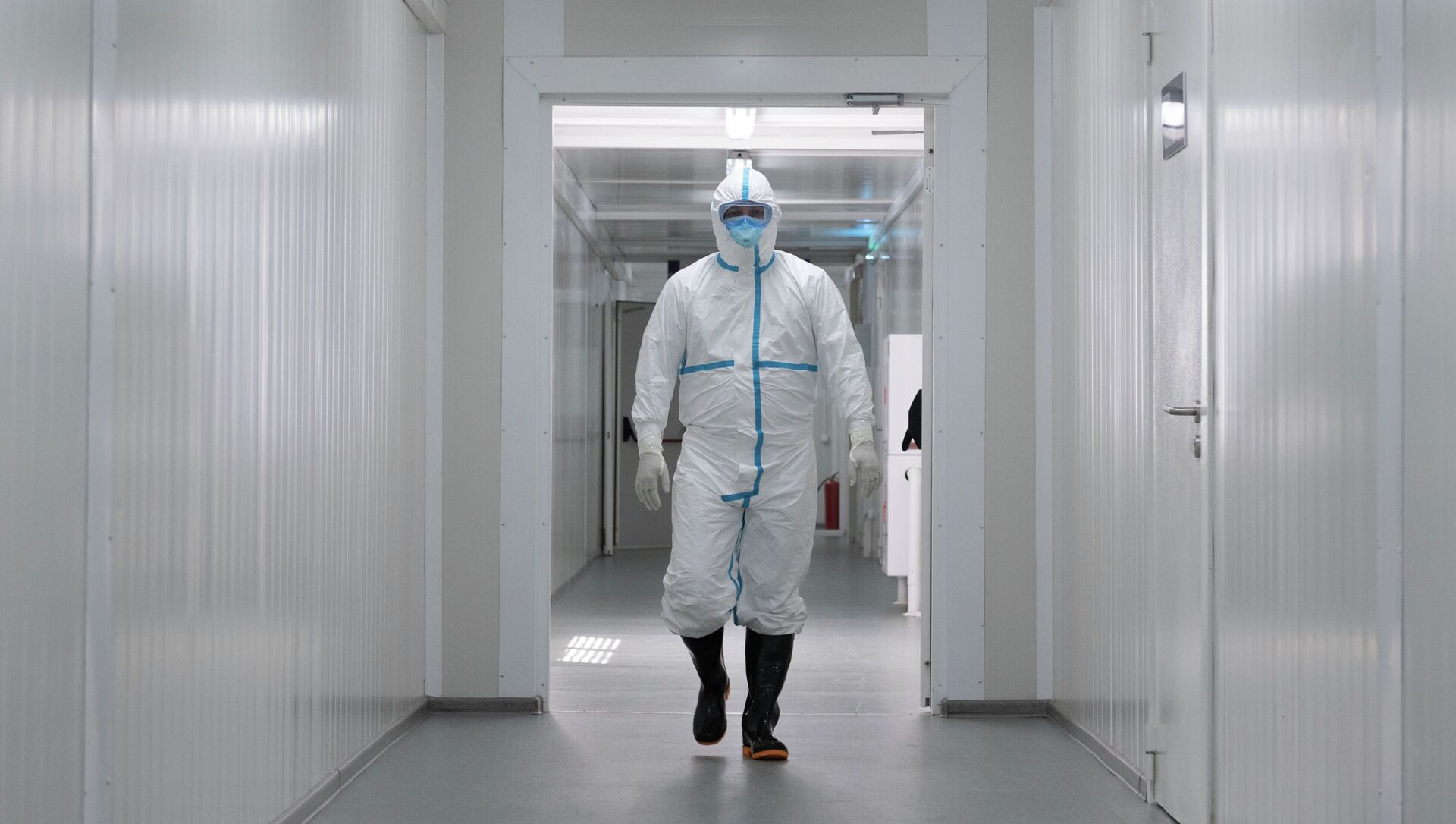 Медик в защитном костюме идет по коридору инфекционного госпиталя в Алматы  - Sputnik Қазақстан, 1920, 16.03.2021