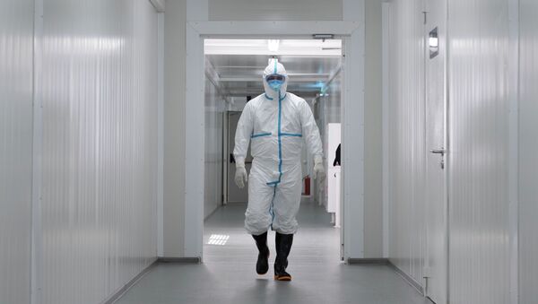 Медик в защитном костюме идет по коридору инфекционного госпиталя в Алматы  - Sputnik Казахстан