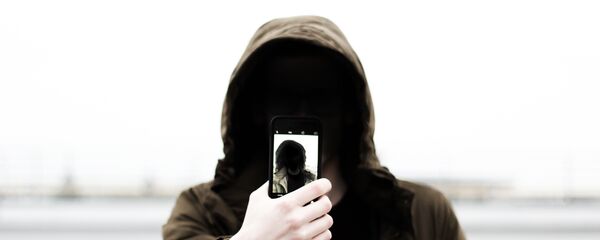 Человек в капюшоне с телефоном в руке - Sputnik Казахстан