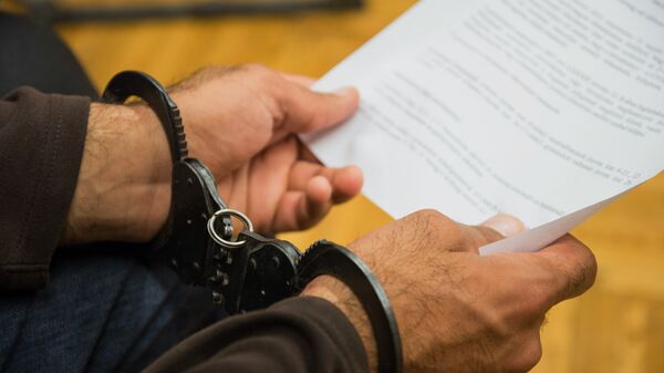 Человек в наручниках держит официальный документ, фото из архива - Sputnik Қазақстан