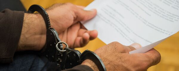 Человек в наручниках держит официальный документ, фото из архива - Sputnik Казахстан