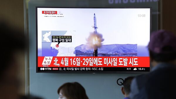 Люди на железнодорожном вокзале в Сеуле смотрят репортаж о Северной Корее, которая произвела в ночь на 14 мая 2017 года пуск баллистической ракеты  - Sputnik Казахстан