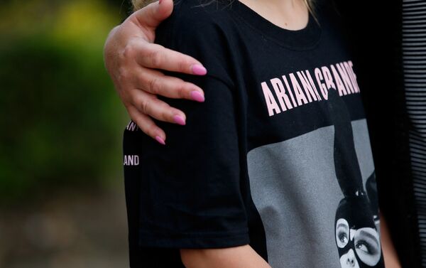 Посетитель концерта в футболке с изображением певицы Арианы Гранде на месте преполагаемого теракта в Манчестере - Sputnik Казахстан