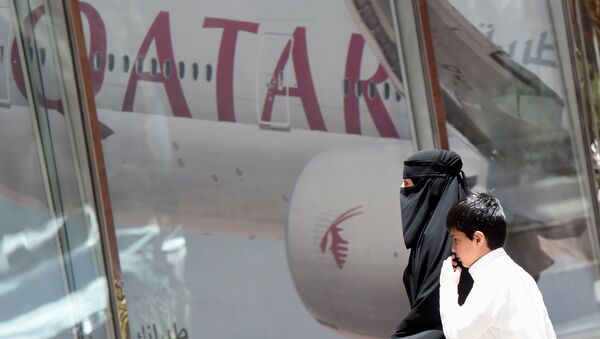 Женщина и мальчик идут мимо офиса Qatar Airways в столице Саудовской Аравии Эр - Рияде, архивное фото - Sputnik Қазақстан