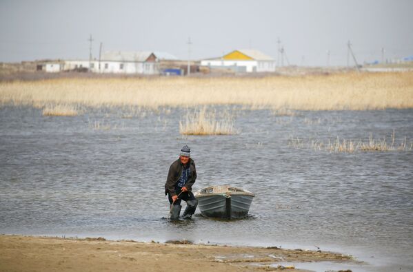 Сельский житель привязывает лодку на берегу Аральского моря, архивное фото - Sputnik Казахстан