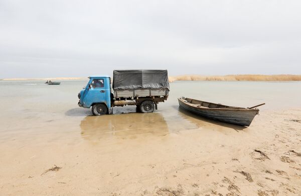 Рыбаки на грузовике  собирают рыбу с лодки на мелководье по Аральскому морю - Sputnik Казахстан