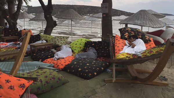 Люди спят на пляже, проведя ночь на свежем воздухе после землетрясения в Битез, курортном городе, расположенном примерно в 6 км к западу от Бодрума, Турция, в пятницу, 21 июля 2017 года - Sputnik Казахстан