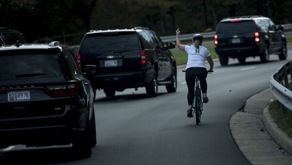Женщина на велосипеде проезжает мимо кортежа президента США с Дональдом Трампом в Стерлинге, штат Вирджиния - Sputnik Казахстан