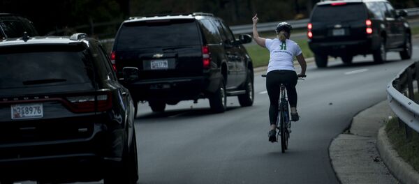 Женщина на велосипеде проезжает мимо кортежа президента США с Дональдом Трампом в Стерлинге, штат Вирджиния - Sputnik Казахстан