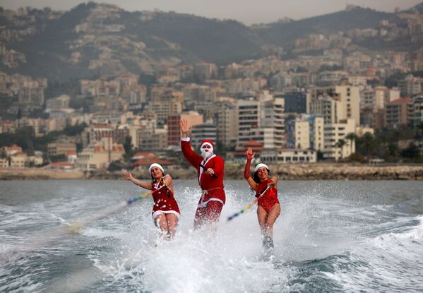 Санта-Клаус боп киінген қыздар Ливандағы Джуния шығанағында жүйрік аттай толқындарға мініп, желдей есіп барады. - Sputnik Қазақстан