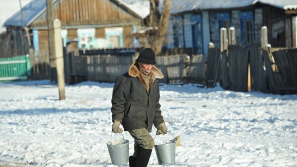 Мужчина несет воду в ведрах по улице села, архивное фото - Sputnik Казахстан