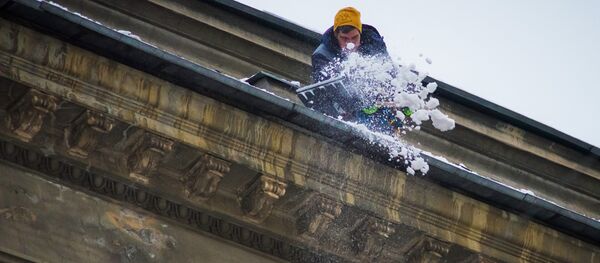 Мужчина очищает от снега крышу дома, архивное фото - Sputnik Казахстан