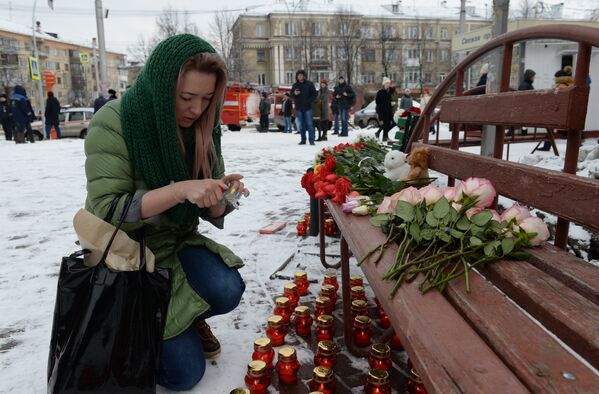 Женщина зажигает свечу возле здания торгового центра «Зимняя вишня» в Кемерово, где произошел пожар. - Sputnik Казахстан