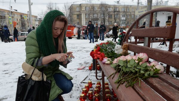 Женщина зажигает свечу в память о погибших в Кемерово - Sputnik Казахстан