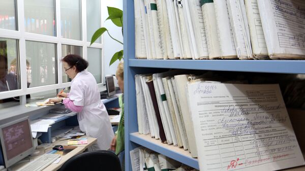 Медицинский работник выдает медицинскую карту пациенту в регистратуре, архивное фото - Sputnik Қазақстан