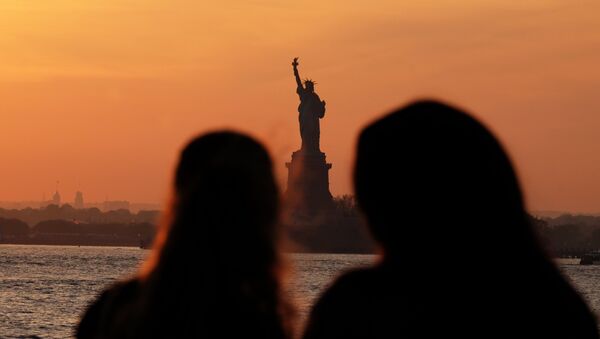 Молодые люди смотрят на Статую Свободы в Нью-Йорке на фоне заходящего солнца - Sputnik Казахстан