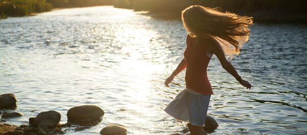 Женщина стоит на камнях у реки, иллюстративное фото Женщина стоит на камнях у реки, иллюстративное фото - Sputnik Казахстан