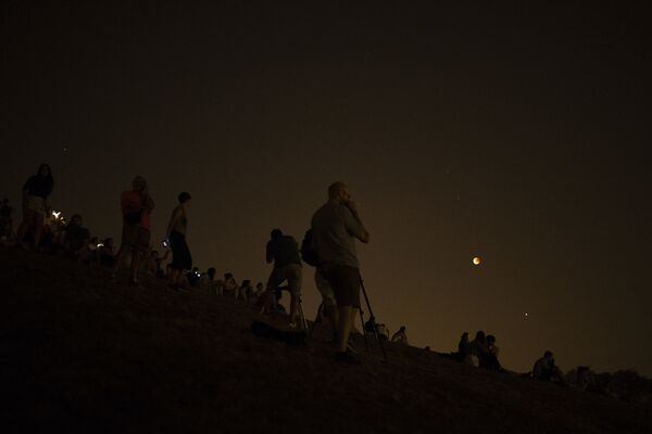 Люди смотрят с вершины холма на красную луну во время полного лунного затмения на парке Серро дель Тио Пио в Мадриде - Sputnik Казахстан
