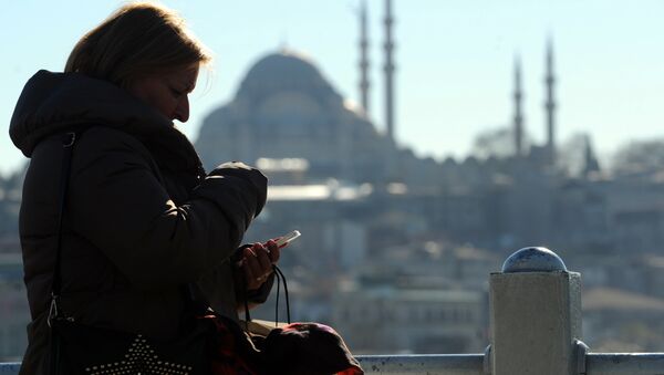 Турецкая женщина смотрит на свой айфон в Стамбуле на фоне мечети, архивное фото - Sputnik Казахстан