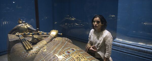 Женщина рассматривает золотой саркофаг фараона Тутанхамона, выставленный в Египетском музее в столице Каире - Sputnik Казахстан