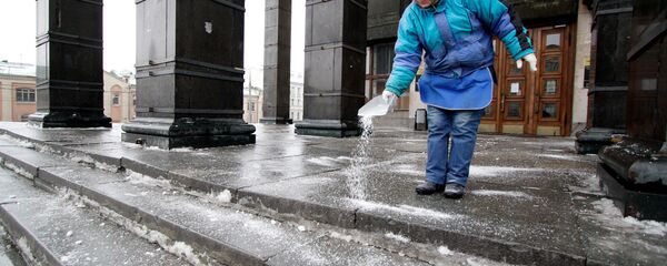 Женщина посыпает реагентом ступеньки во время гололеда - Sputnik Казахстан