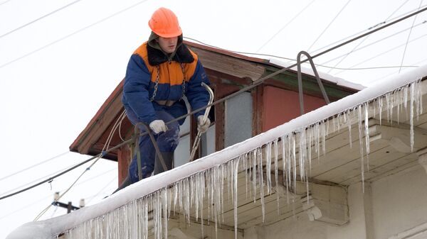 Работник жилищно-коммунальной службы сбивает сосульки с крыши, архивное фото - Sputnik Казахстан