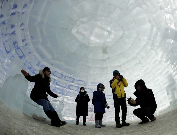 Люди фотографируются в иглу, построенного для зимних Олимпийских игр 2018 года в Пхенчхане, Южная Корея - Sputnik Казахстан