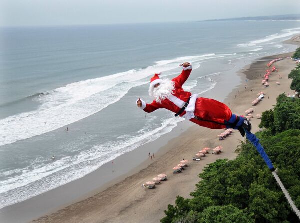 Мужчина в костюме Санта-Клауса во время банджи-джампинга на острове Бали - Sputnik Казахстан