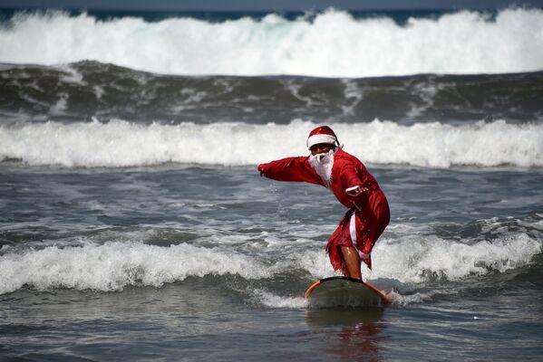 Мужчина в костюме Санта-Клауса во время серфинга на острове Бали - Sputnik Казахстан