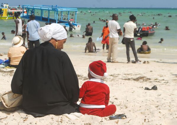 Мальчик в костюме Санта-Клауса рядом с матерью на пляже в Кении - Sputnik Казахстан