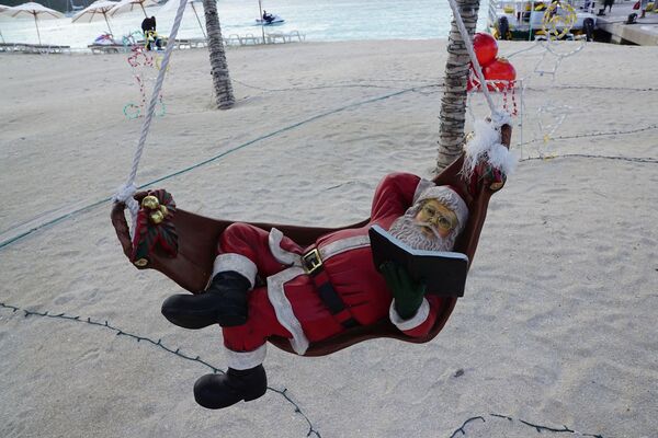 Санта-Клаус во время чтения книги на пляже острова Сен-Мартен - Sputnik Казахстан