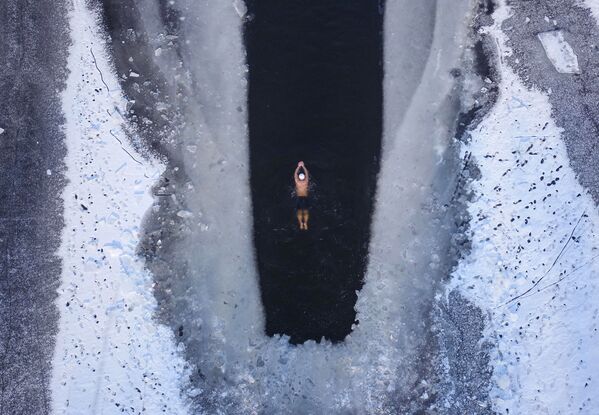 Человек плавает в частично замерзшем озере в Шэньяне, провинция Ляонин - Sputnik Казахстан