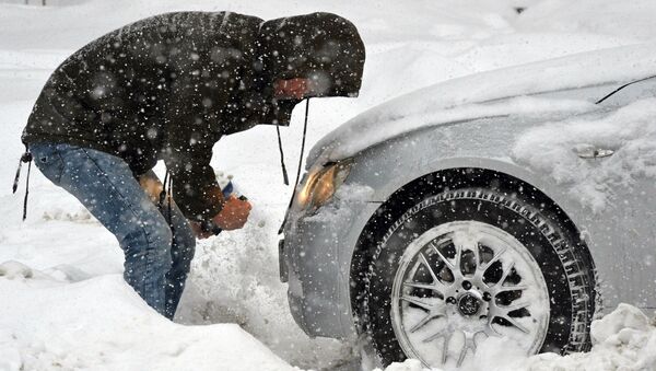 Мужчина очищает занесенную снегом машину - Sputnik Қазақстан