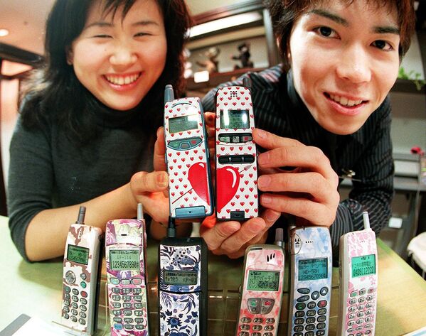 Молодая японская пара демонстрирует свои мобильные телефоны с дизайнерскими клеймами в универмаге Токи, 1999 год. - Sputnik Казахстан